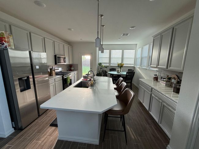 Kitchen featuring appliances with stainless steel finishes, wood finish floors, tasteful backsplash, light countertops, and recessed lighting | Image 24