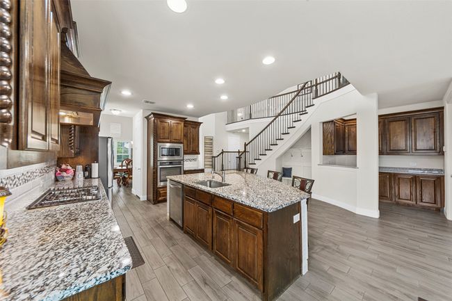 Kitchen with stainless steel appliances, a sink, light wood-type flooring, baseboards, and recessed lighting | Image 11