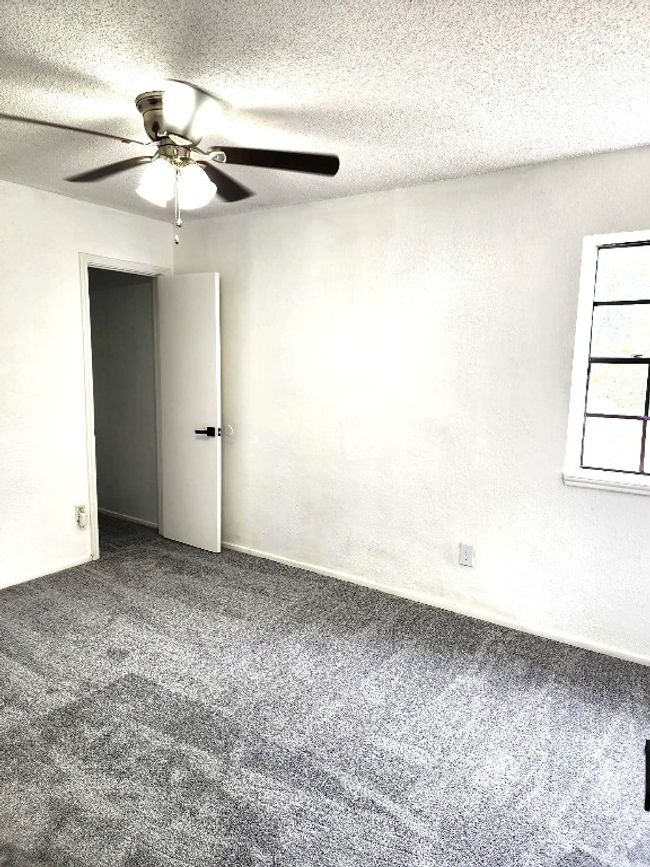 Carpeted spare room with ceiling fan and a textured ceiling | Image 9