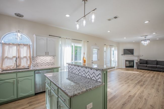 Kitchen featuring dishwasher, visible vents, a sink, and green cabinetry | Image 5