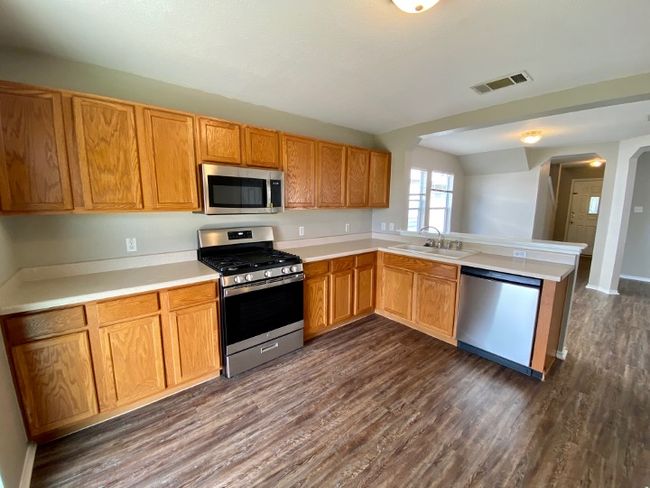 Kitchen with stainless steel appliances, dark wood-style floors, a peninsula, and light countertops | Image 13