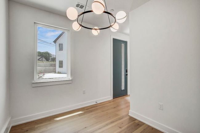 Spare room featuring light wood-type flooring, baseboards, and a chandelier | Image 18