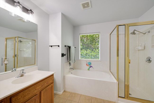 Bathroom featuring a stall shower, a garden tub, vanity, and tile patterned flooring | Image 13