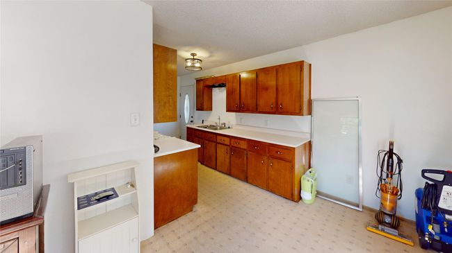Kitchen featuring light countertops, brown cabinetry, and a textured ceiling | Image 9