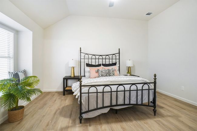 Bedroom with light wood-style floors, baseboards, vaulted ceiling, and ceiling fan | Image 14