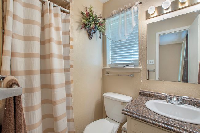 Full bathroom featuring toilet, a shower with curtain, vanity, and a textured wall | Image 7