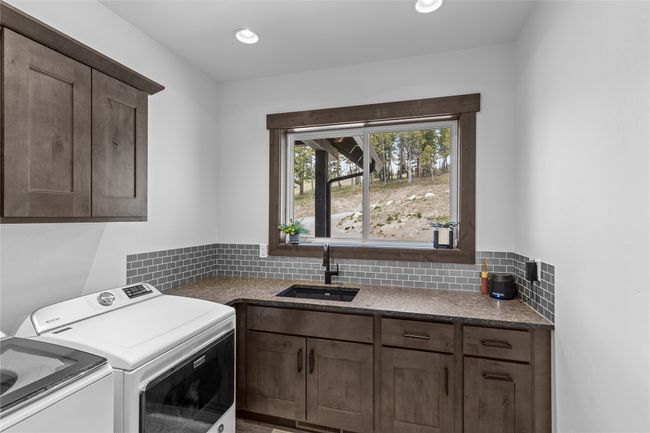 Clothes washing area with separate washer and dryer, cabinet space, recessed lighting, and a sink | Image 34