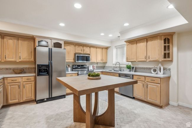 Kitchen featuring recessed lighting, a sink, stainless steel appliances, glass insert cabinets, and light countertops | Image 7