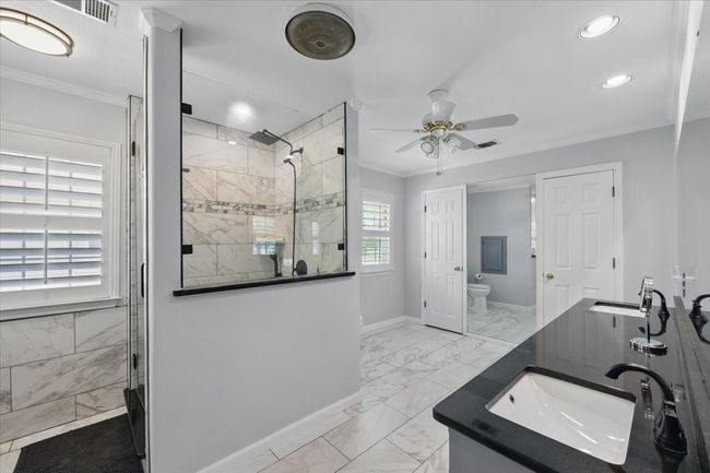 Bathroom featuring marble look tile flooring, tiled shower, a ceiling fan, baseboards, and vanity | Image 17