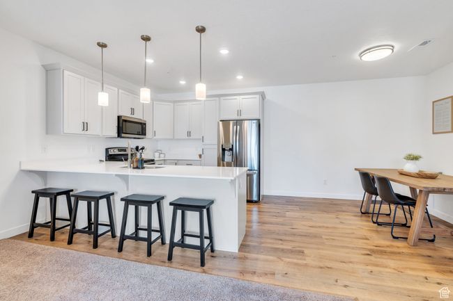 Kitchen with light countertops, a kitchen breakfast bar, a peninsula, recessed lighting, and stainless steel appliances | Image 5