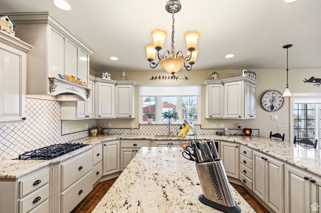 Kitchen with white cabinetry, a wealth of natural light, pendant lighting, and stainless steel gas stovetop | Image 29