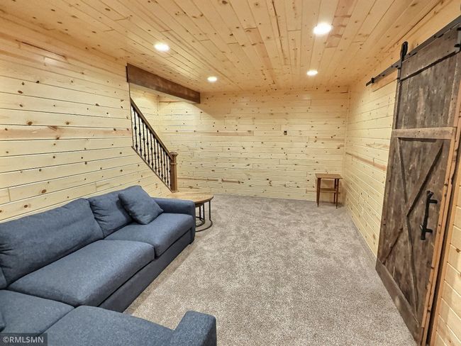 The lower level family room features natural wood work and sliding barn door that opens to the utility room. | Image 25