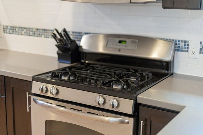 Kitchen with dark brown cabinets, tasteful backsplash, and stainless steel gas stove | Image 12