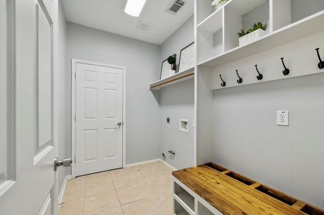Custom built-ins add serious function to the laundry room, with hooks, cubbies, shelving, and bench seating to keep everything organized. | Image 33