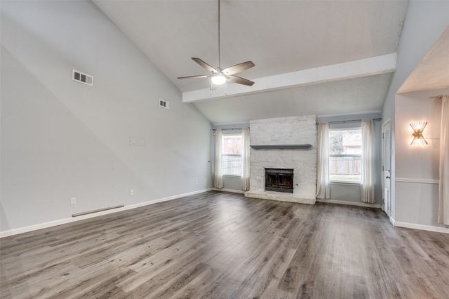 Unfurnished living room featuring ceiling fan, beam ceiling, a fireplace, and hardwood / wood-style flooring | Image 7