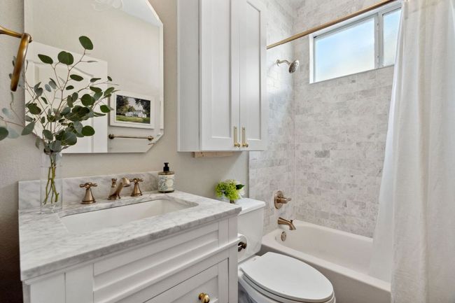 This full guest bathroom is situated next to the guest bedroom and comes beauitfully updated with a contemporary vanity, tasteful finishes, and a shower/tub combo with tile backsplash. | Image 19