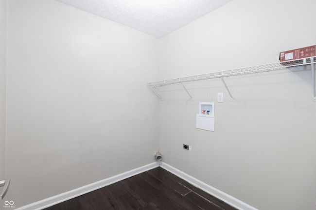 laundry area downstairs with hookup for a washing machine, dark wood-type flooring, and electric dryer hookup | Image 13