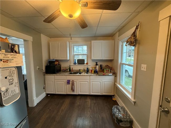 Kitchen featuring stainless steel microwave, white cabinetry, and a sink | Image 12