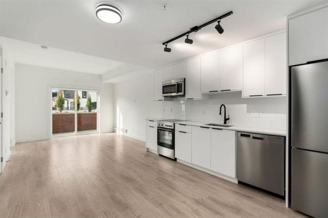 Kitchen with light countertops, appliances with stainless steel finishes, light wood-style floors, white cabinets, and a sink | Image 5