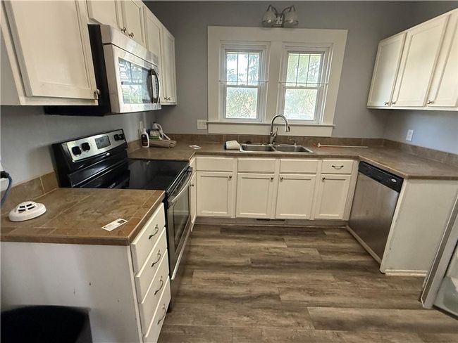 Kitchen featuring stainless steel appliances, a sink, white cabinets, and dark wood-style flooring | Image 8