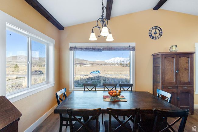 Dining room featuring lofted ceiling with beams, baseboards, dark wood-type flooring, and a chandelier | Image 16