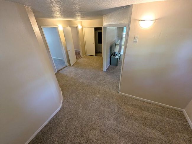Hall featuring light carpet, a textured ceiling, and baseboards | Image 13