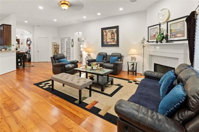 Bright & inviting family living room with a cozy gas fireplace and stylish wood flooring. | Image 1