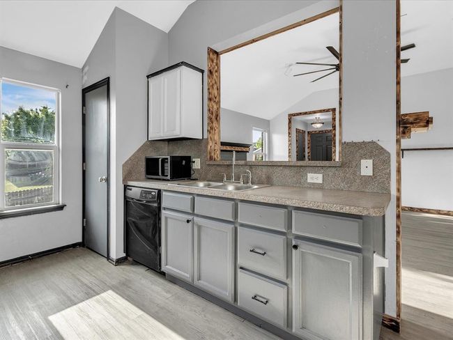 Kitchen featuring stainless steel microwave, a sink, vaulted ceiling, black dishwasher, and gray cabinets | Image 6