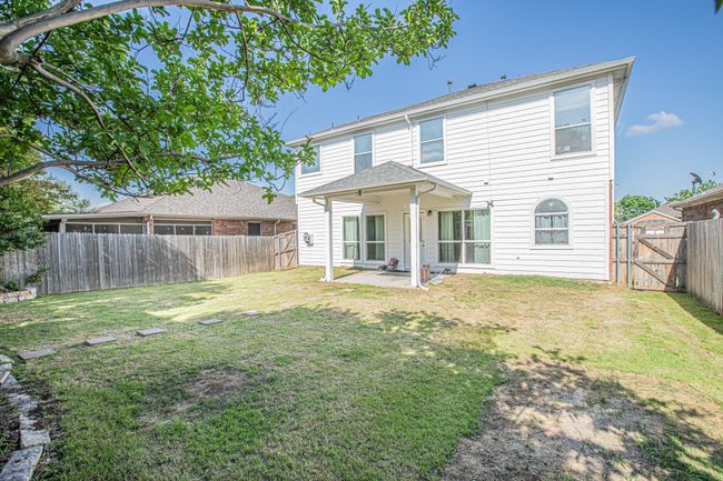 Back of house with a fenced backyard, a gate, a yard, and a patio | Image 23