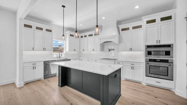 Kitchen with custom exhaust hood, light wood-style flooring, appliances with stainless steel finishes, and a sink | Image 16