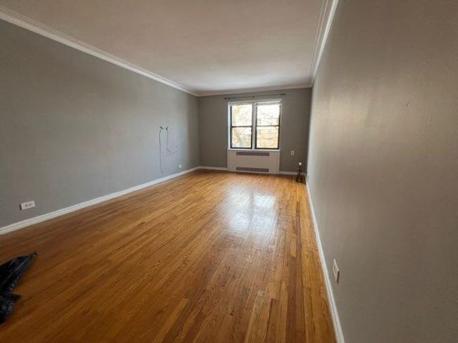 Empty room with radiator, wood finished floors, baseboards, and ornamental molding | Image 4