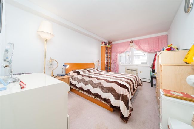 Carpeted bedroom featuring a baseboard radiator and a wall mounted air conditioner | Image 4
