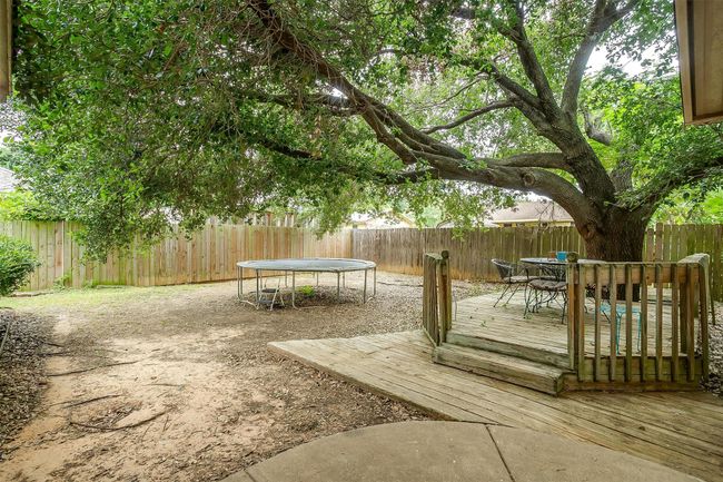 Wooden terrace with a fenced backyard, a trampoline, and outdoor dining space | Image 37