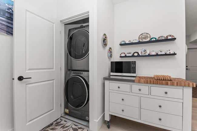 Laundry room with stacked washer / drying machine and light wood finished floors | Image 35