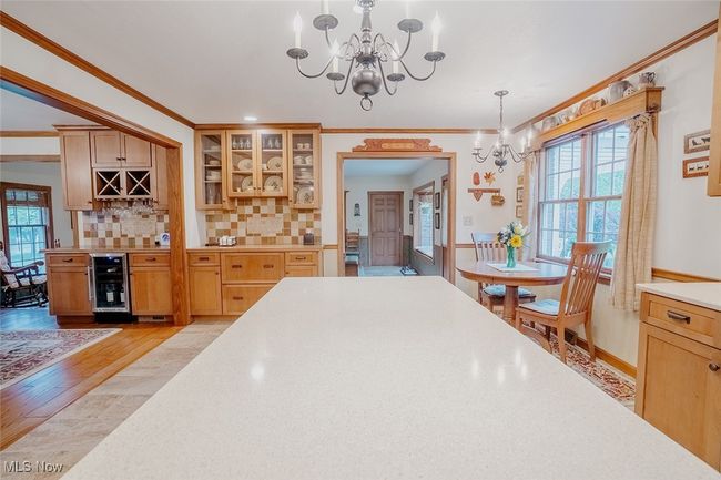 Main kitchen with beverage cooler, a chandelier, ornamental molding, bar area, and light wood finished floors | Image 8