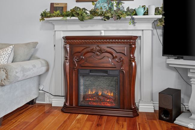 Interior details with a lit fireplace and wood finished floors | Image 5