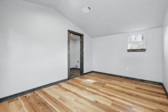 Unfurnished room with visible vents, baseboards, lofted ceiling, and hardwood / wood-style floors | Image 23