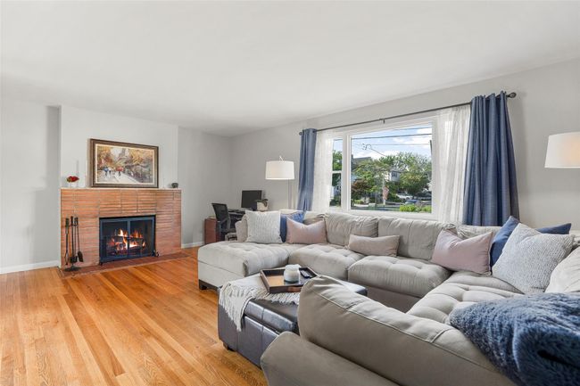 Living room featuring light wood-type flooring, a brick fireplace, and baseboards | Image 5