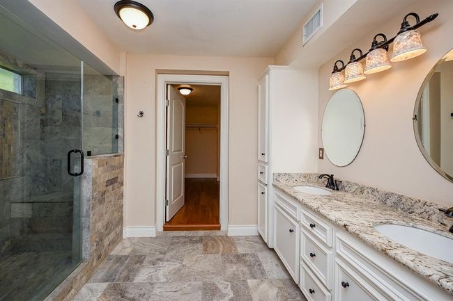 Master bathroom as you enter from the bedroom. The luxurious master bathroom features a spacious walk-in shower, granite vanity, double sinks, and beautiful tile floors. The bathroom leads into a spacious master closet. | Image 18