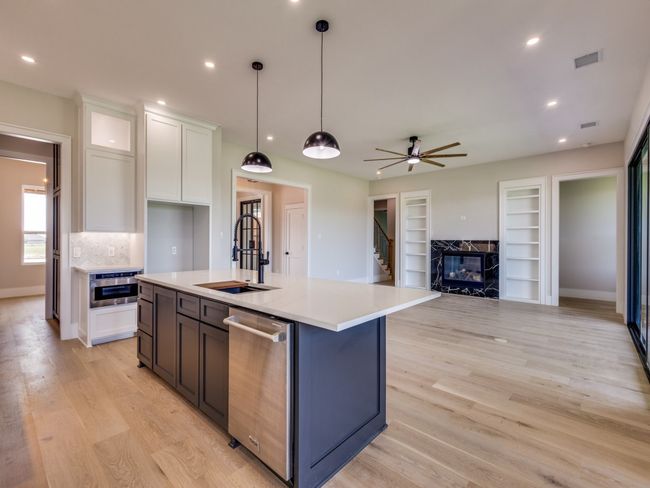 Kitchen featuring stainless steel Thor dishwasher, a sink, white custom cabinets, light countertops, and recessed lighting, pop of color on kitchen island base. | Image 23