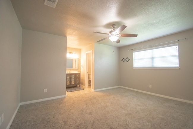 Unfurnished bedroom featuring carpet, a textured ceiling, connected bathroom, baseboards, and ceiling fan | Image 15