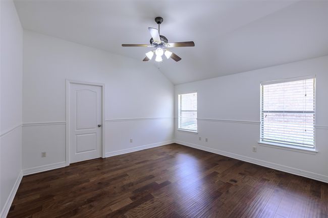 Spare room featuring lofted ceiling, dark wood-style flooring, baseboards, and ceiling fan | Image 9