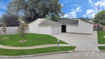 Suburban single-story house with a double garage, manicured lawn, and a mailbox, under a clear sky. | Image 3