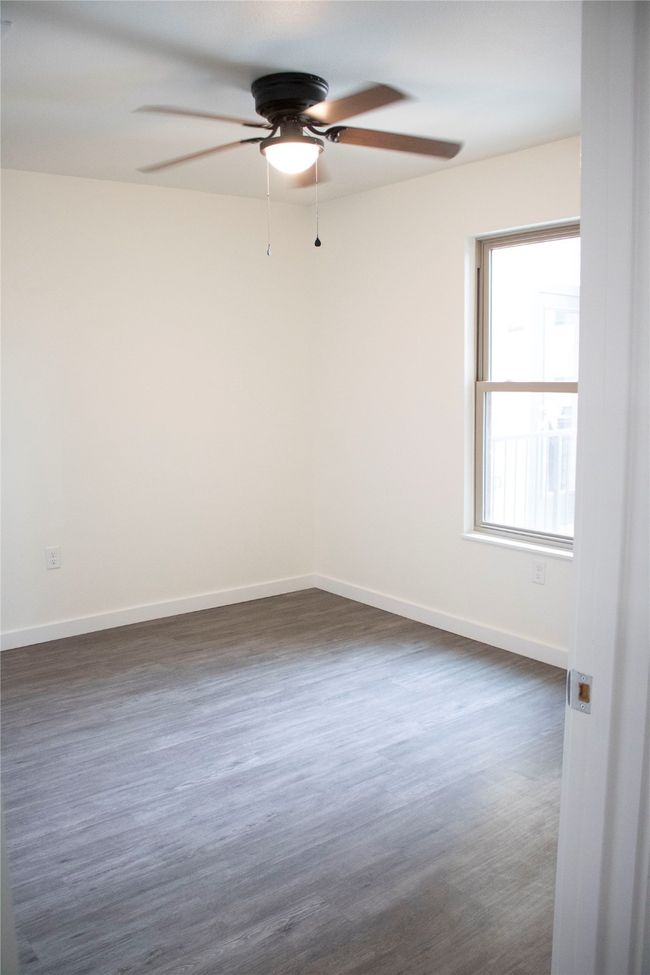 Empty room with a ceiling fan, baseboards, and dark wood finished floors | Image 5