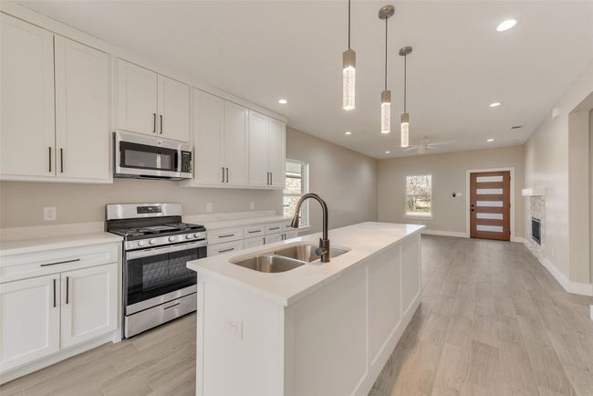 Kitchen with appliances with stainless steel finishes, white cabinetry, light wood finished floors, ceiling fan, and recessed lighting | Image 10