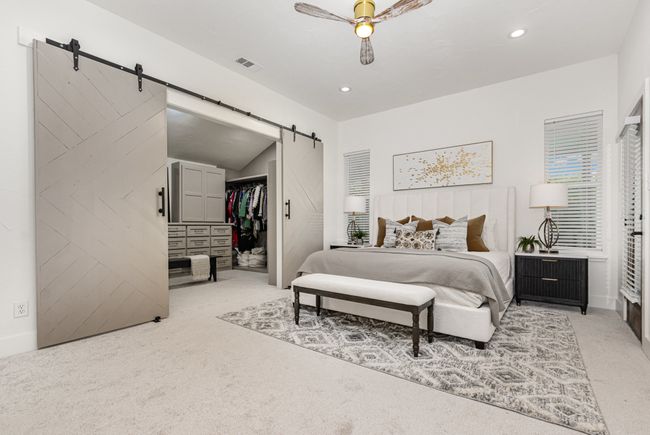 Bedroom featuring a barn door, a spacious closet, light colored carpet, ceiling fan, and recessed lighting | Image 15