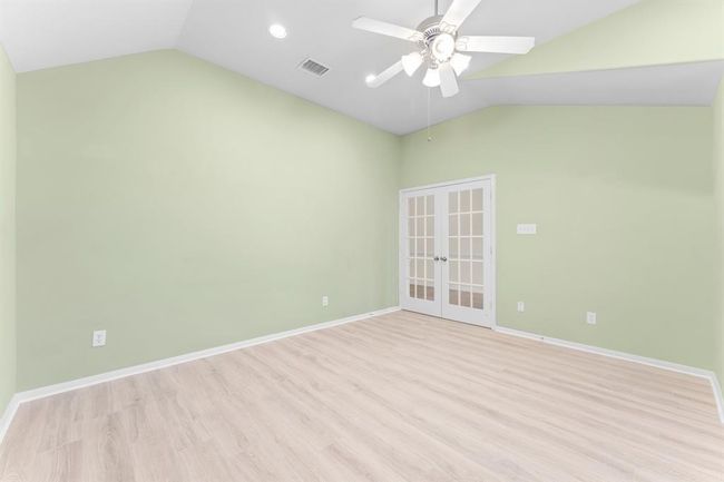 Another view of the study featuring high vaulted ceilings, recessed lighting, and a large arched window with peaceful views of the front yard. French doors add both charm and privacy, making this space as functional as it is beautiful. | Image 5
