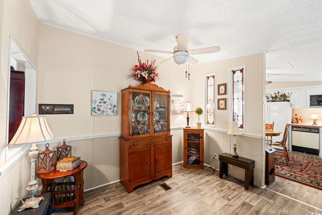 Sitting room featuring light wood-style flooring, a textured ceiling, a ceiling fan, a decorative wall, and a wainscoted wall | Image 17