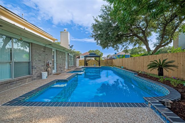 Backyard oasis features a saltwater pool and hot tub, all surrounded by a brand-new perimeter fence. Enjoy outdoor living under the pergola, with plenty of space to relax or entertain. Robotic pool cleaners are included for easy maintenance. Spacious yard extends to the side, perfect for play or gardening. | Image 37
