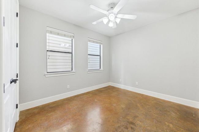 The secondary bedroom on the first floor with neutral walls and a polished concrete floor and large closet. | Image 22
